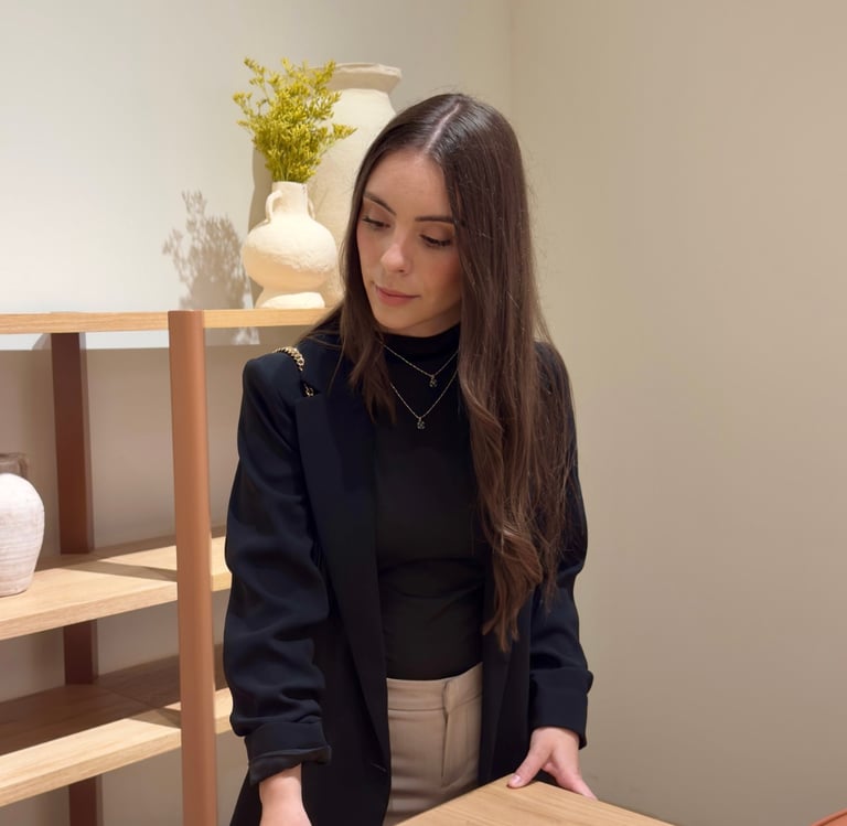 A stylish woman in a black blazer browsing wooden furniture in a modern minimalist home decor store.