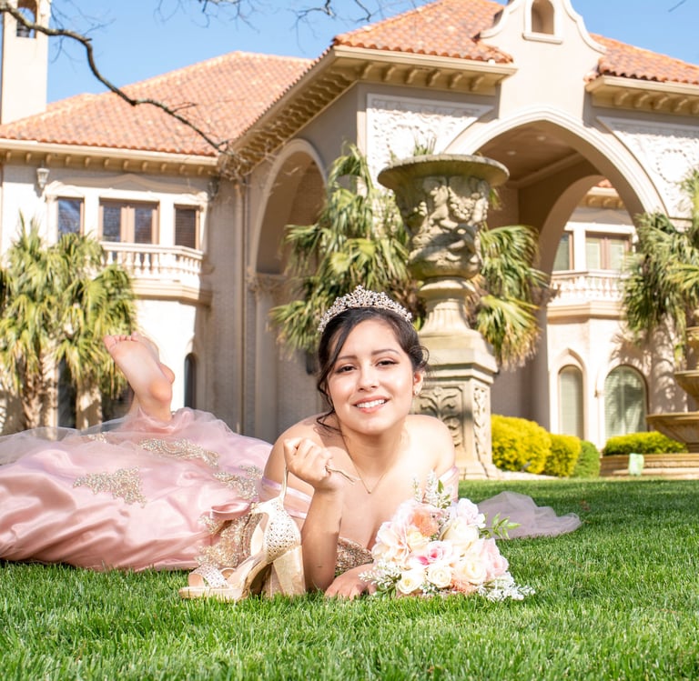 quinceanera princess in a pink dress laying on the grass