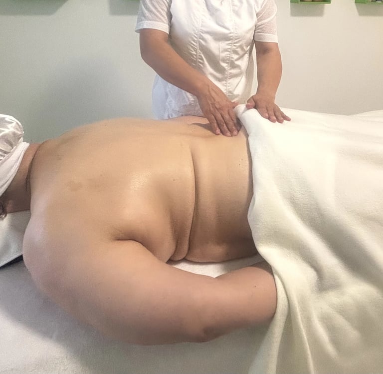 Séance de massage du dos dans une salle de soins, avec une praticienne massant une personne allongée