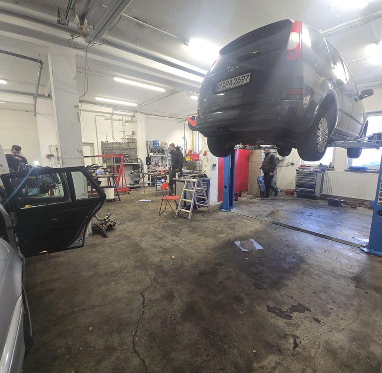 Auto wird in der KFZ-Werkstatt mit einer Hebebühne für Inspektion oder Reparaturen angehoben.