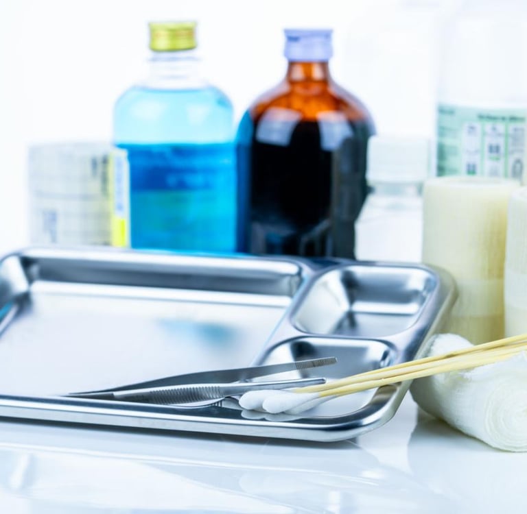 Medical dressing kit with stainless steel tray, forceps, gauze rolls, and antiseptic solution bottles.