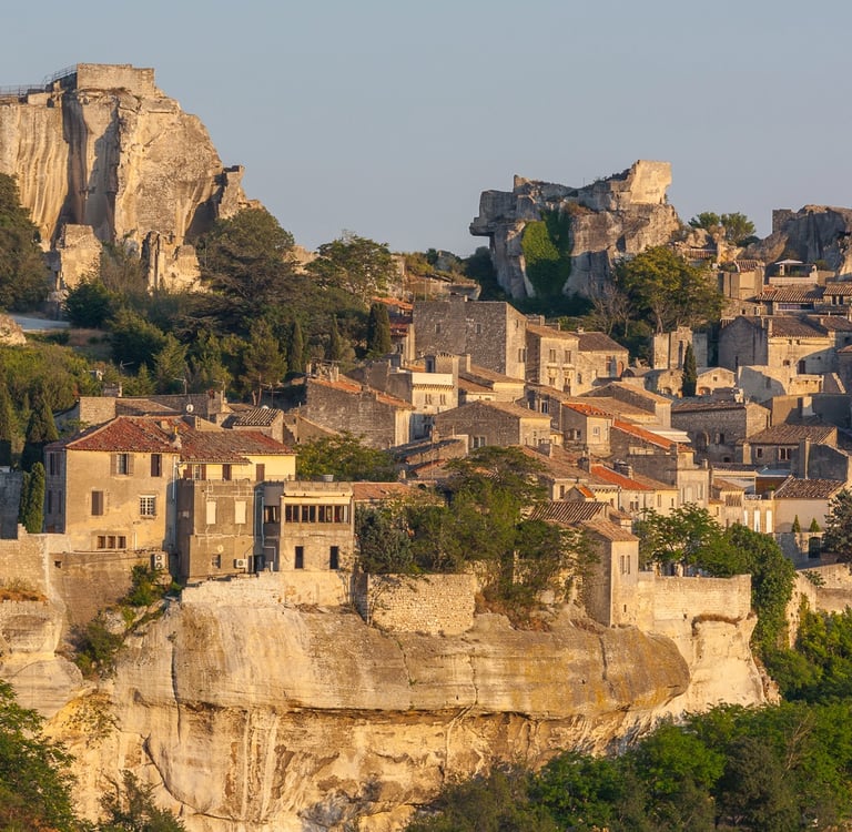 Panoramic view of the historic Les Baux-de-Provence village and its medieval fortress ruins on a rocky cliff.