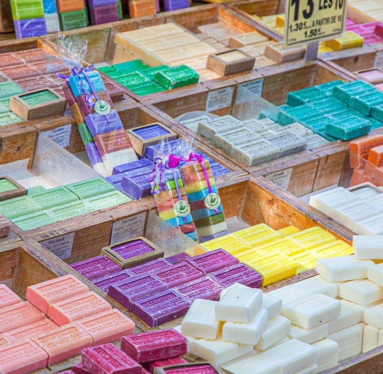 Display of colorful artisan soaps in wooden crates at an outdoor French market.