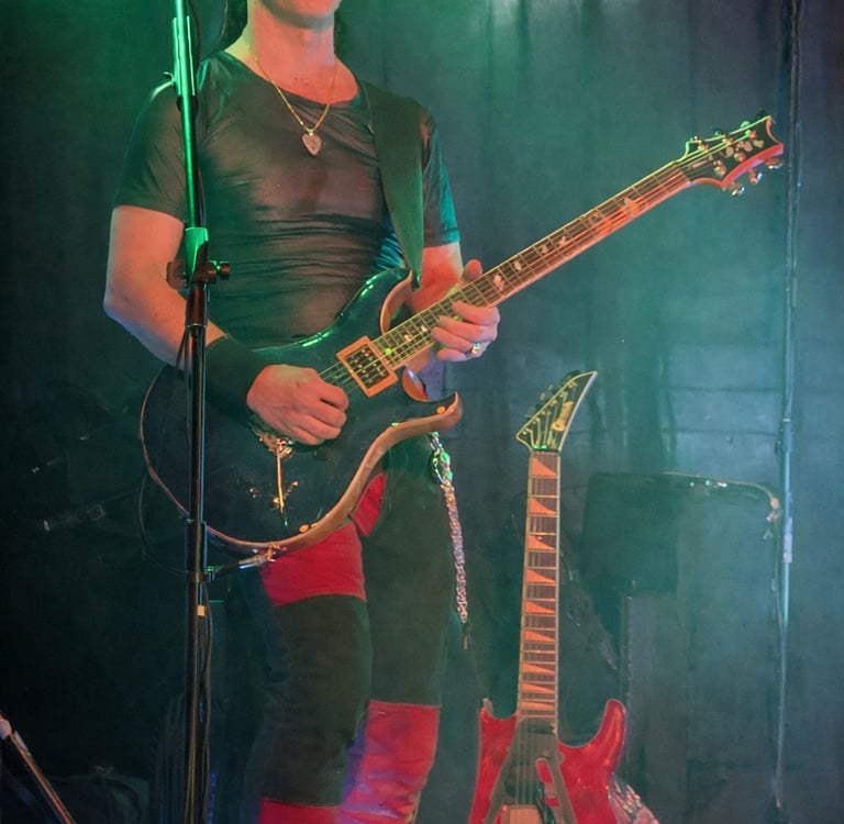 Dan performing live on stage with a blue PRS electric guitar under green stage lighting.
