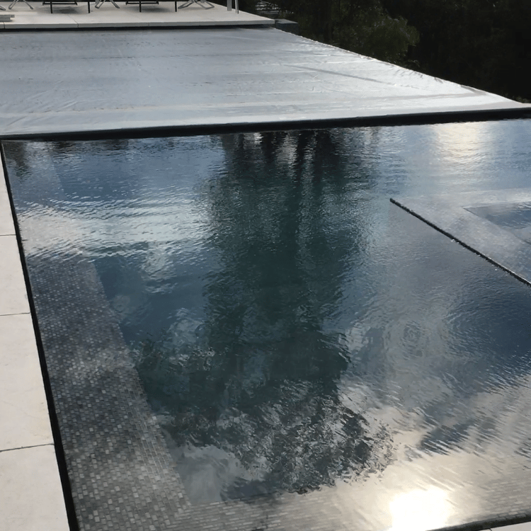 a perimeter flow pool with an automatic pool cover and a sky view 