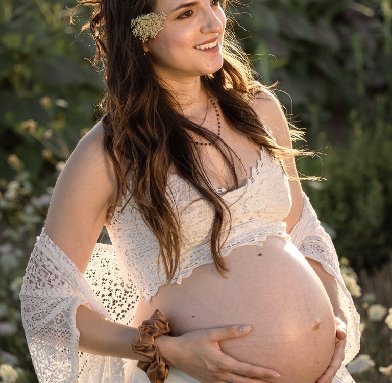 a pregnant woman in a white dress and sunflowers