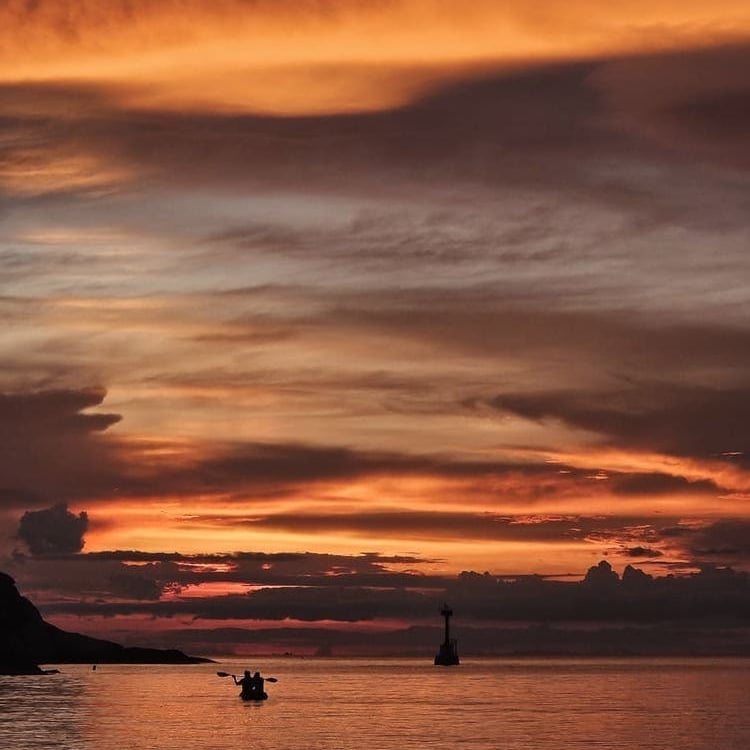 sunset in the ocean and people kayaking