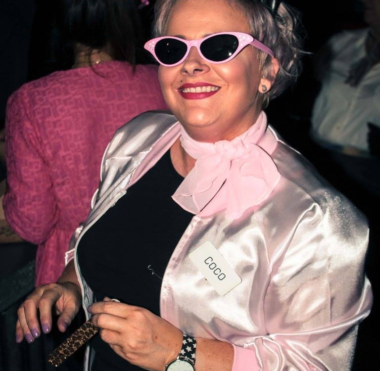 a woman is dressed in 1950s costume for a murder mystery party. She is wearing sunglasses and kitten ears.