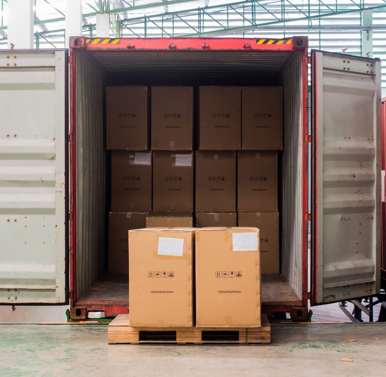Stacked cardboard boxes inside an open red shipping container for freight transport.