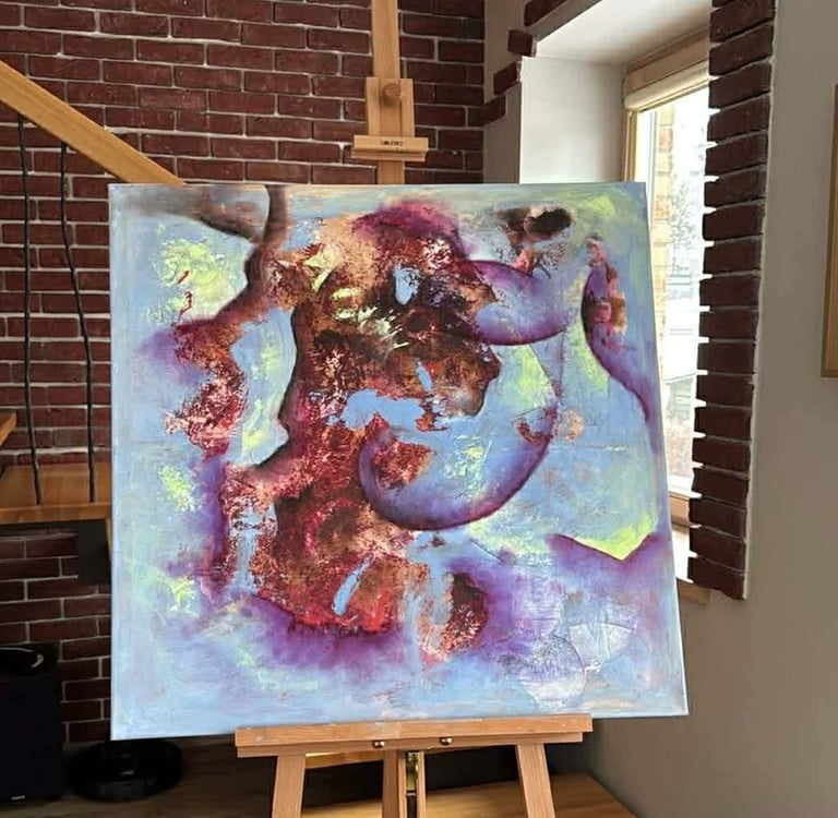 Modern abstract canvas painting with purple and blue hues on a wooden easel in an art studio.