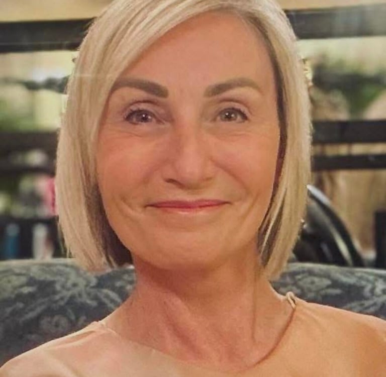 Lisa, smiling, with a blonde bob hairstyle wearing a peach-colored silk blouse.