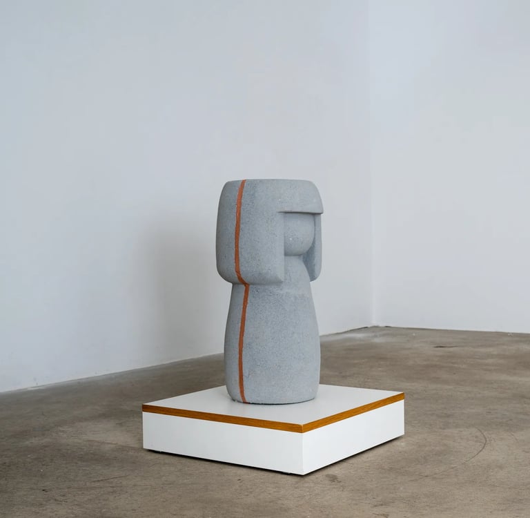 Profilaufnahme einer Kokeshi aus Stein in Blau-Grau. Sie hat eine sichtbare Naht an der Seite