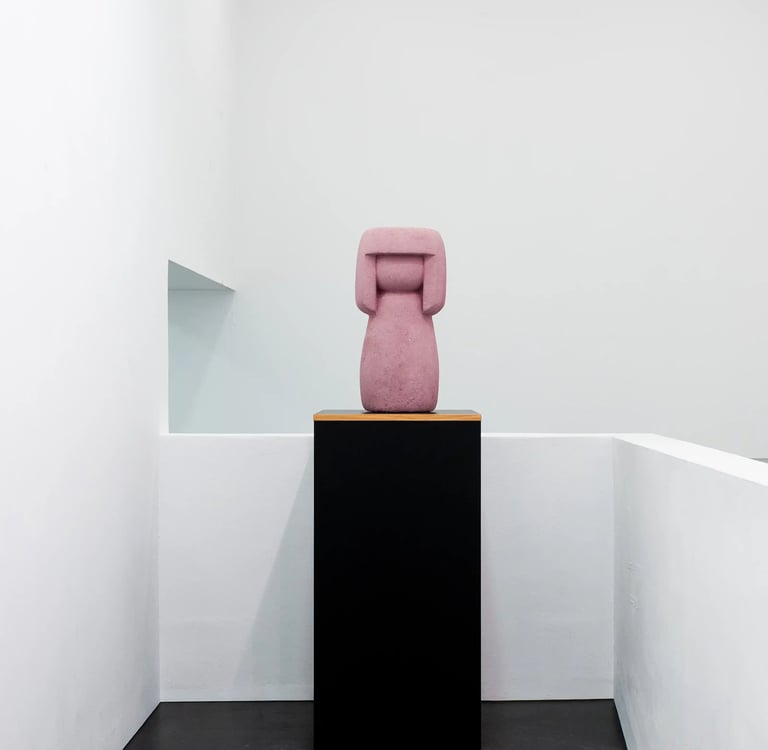 Eine rosa rötliche Kokeshi auf einem Podest im Museum