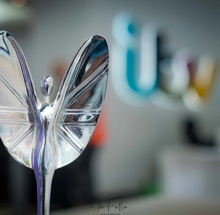 Polished silver trophy figurine with wings in front of a blurred ITV logo background.