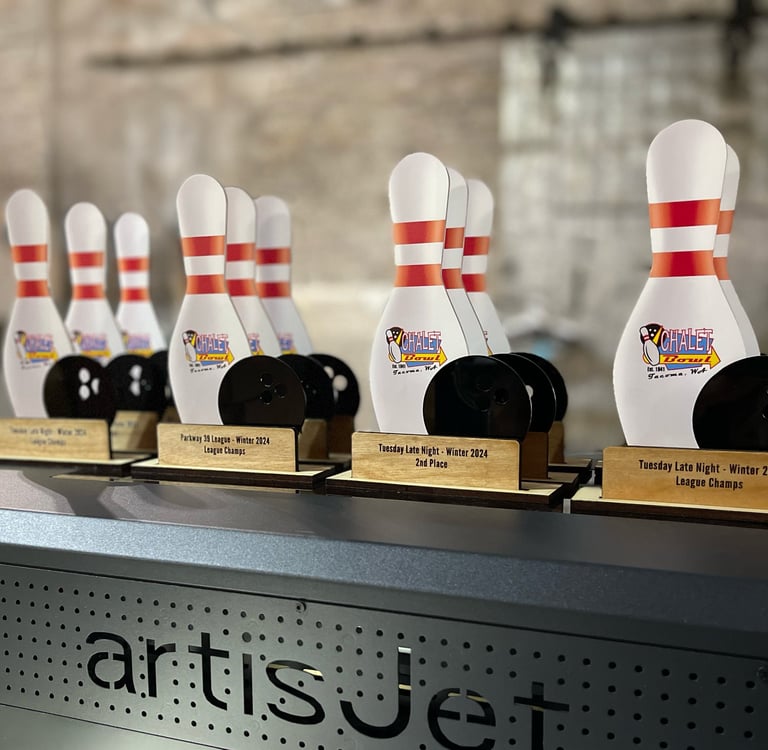 Custom UV printed bowling trophies featuring pins and balls on an artisJet printer bed.