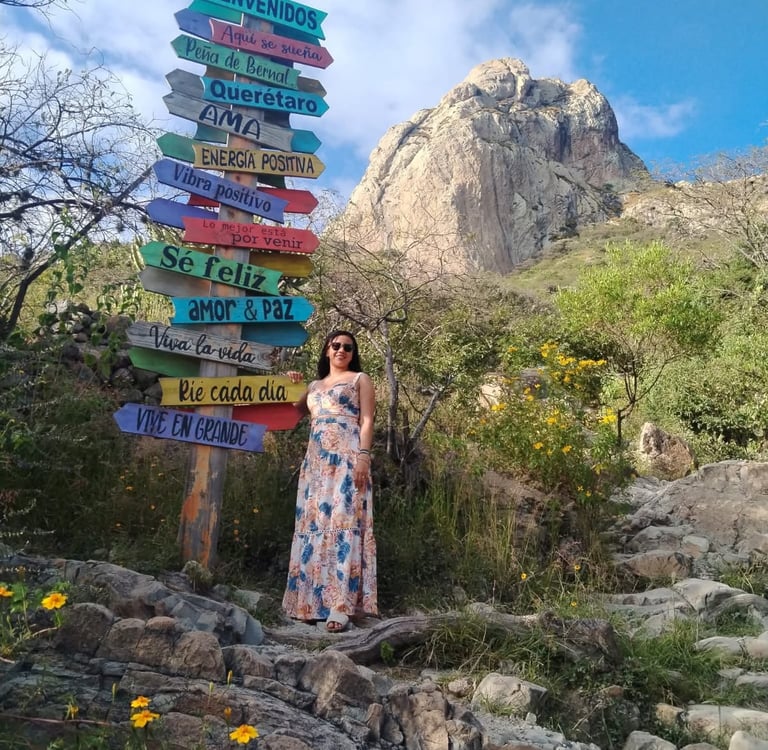 mujer en la peña de bernal posando en letreros direccionales