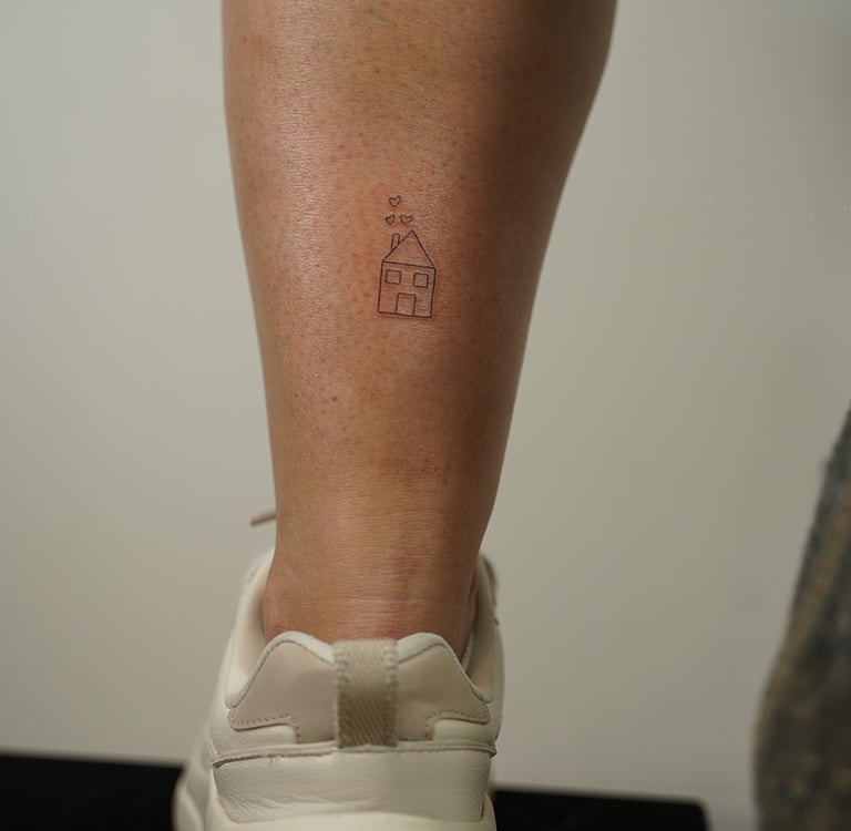 Tatuaje fineline en Madrid de casa pequeña con corazones flotando en trazo fino en el muslo