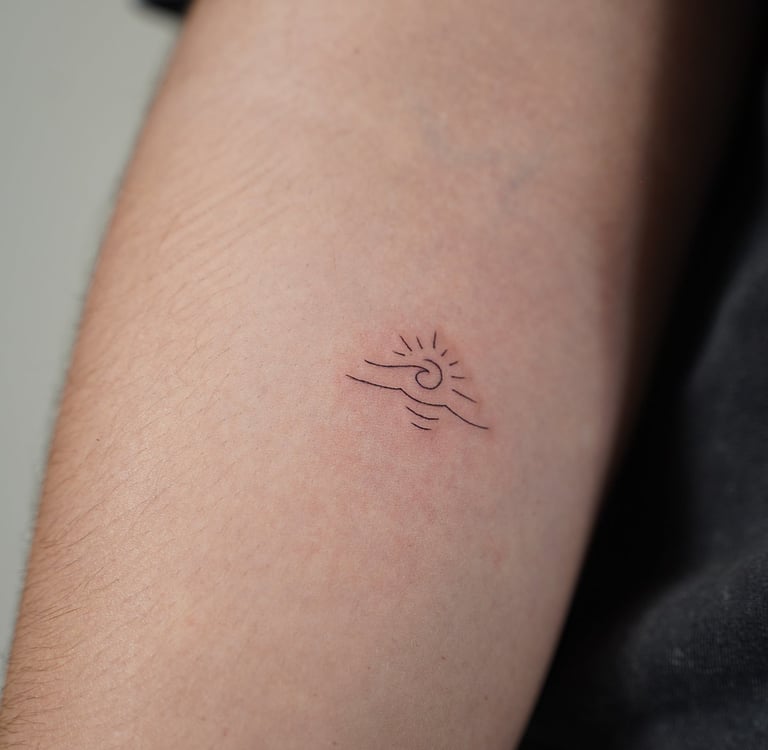 Tatuaje fineline en Madrid de sol con olas minimalista en trazo fino en el antebrazo