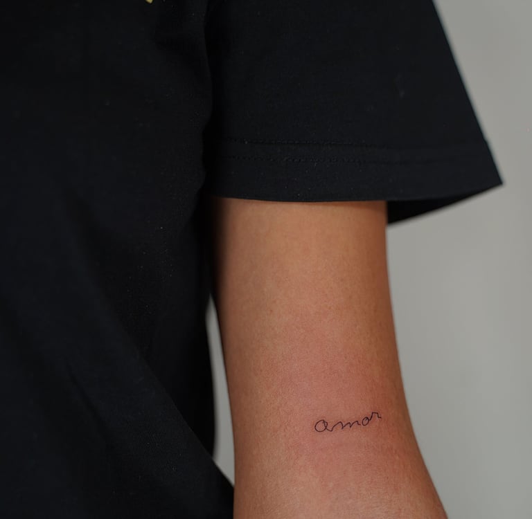 Tatuaje fineline en Madrid con lettering amor en cursiva minúscula trazo fino en el antebrazo
