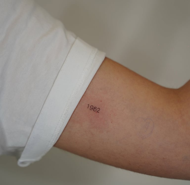 Tatuaje fineline en Madrid de año 1962 en tipografía fina y discreta en el antebrazo