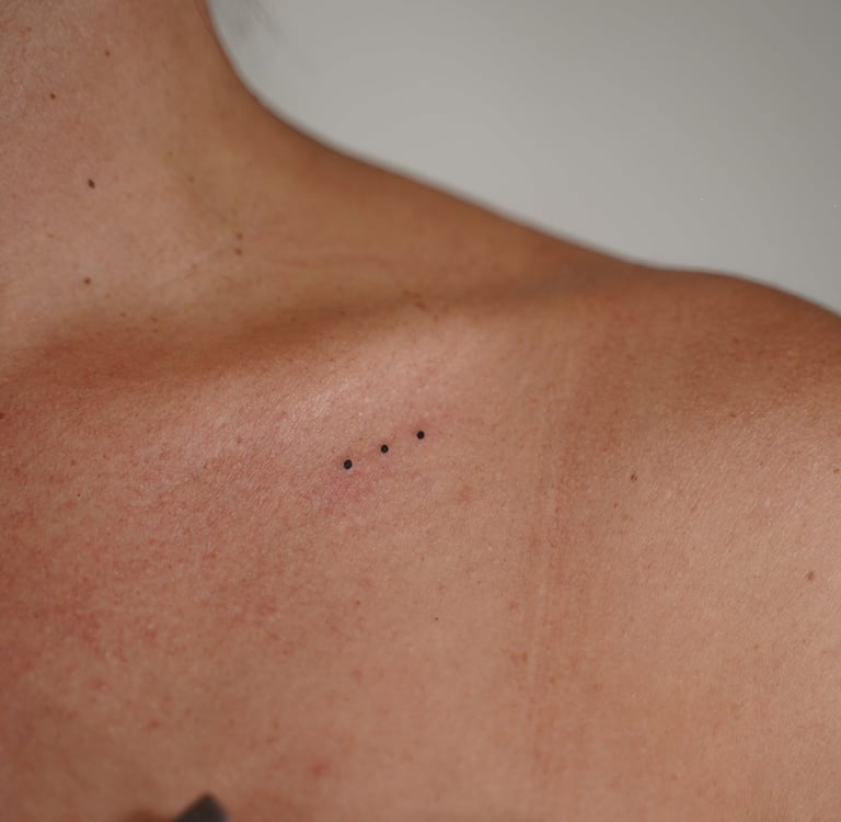 Tatuaje fineline en Madrid de tres puntos micro alineados en tinta negra en la clavícula