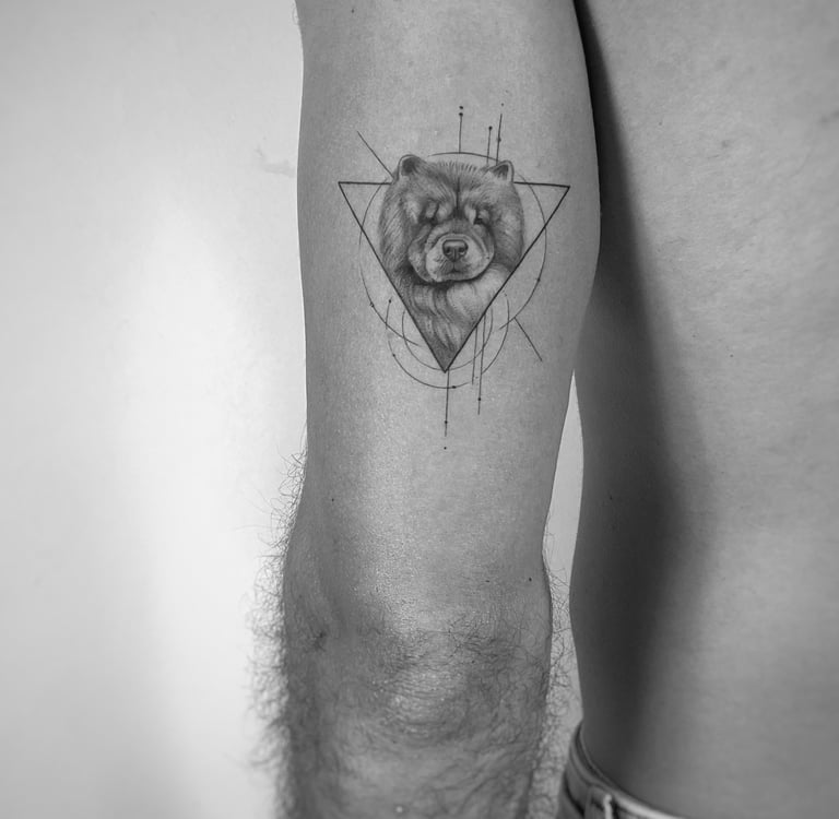 Tatuaje microrealismo perro dentro de triángulo geométrico en brazo madrid