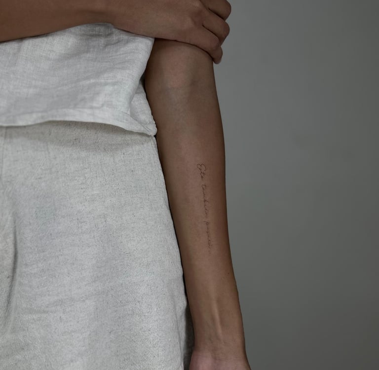Tatuaje fineline en Madrid de frase manuscrita vertical en escritura cursiva muy fina 