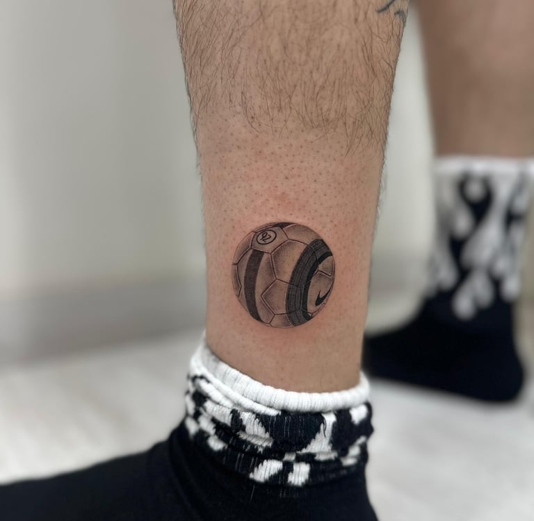 Tatuaje microrealismo en Madrid de balón de fútbol Nike con sombreado fotorrealista en la pierna