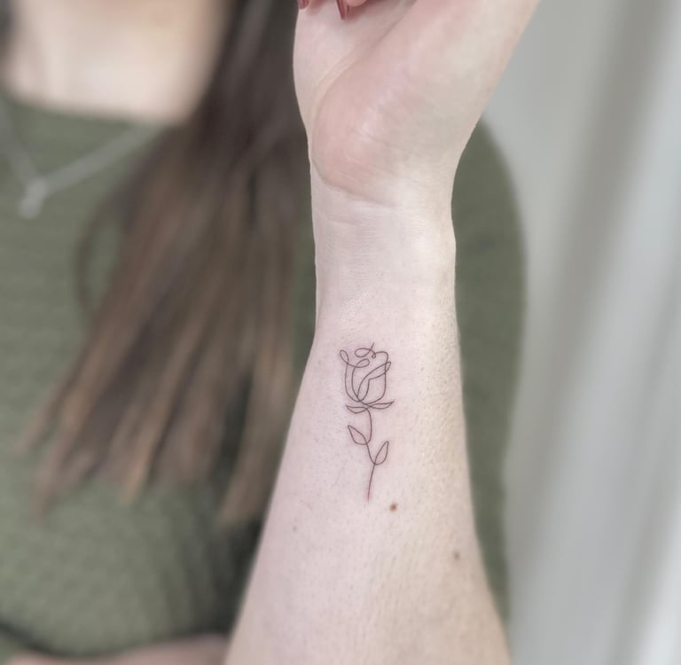 Tatuaje fineline en Madrid de rosa minimalista dibujada con trazo único y continuo