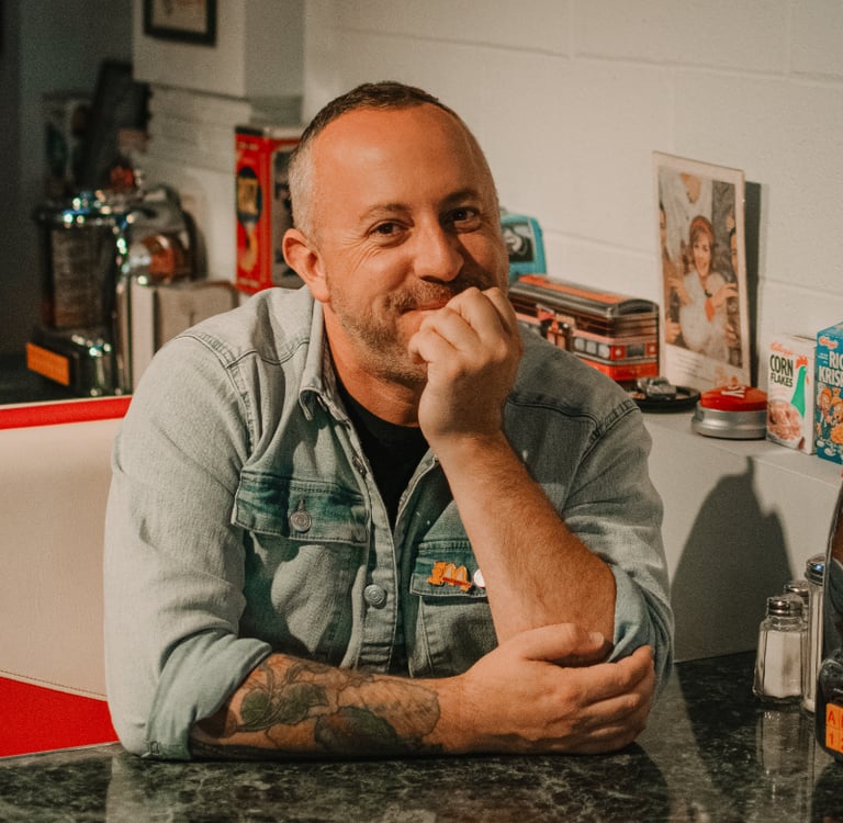 Photo of Dan Clapson sitting in a diner booth, taken in Calgary by Annie da Silva