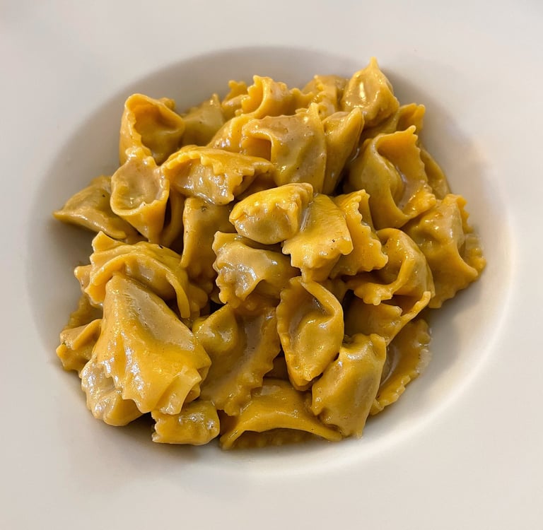 A white bowl filled with handmade Italian agnolotti pasta tossed in a rich butter and sage sauce.