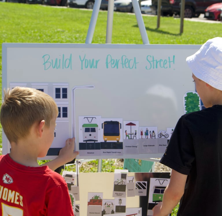 Two children at a whiteboard activity titled "Build Your Perfect Street!"