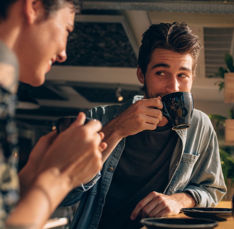 A couple sitting at a kitchen table in Calgary having a calm, focused conversation, natural daylight, coffee cups nearby