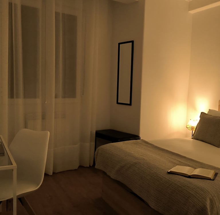 Habitación con cama de matrimonio en Hotel Arias, Vigo, con ventana y escritorio con ordenador.