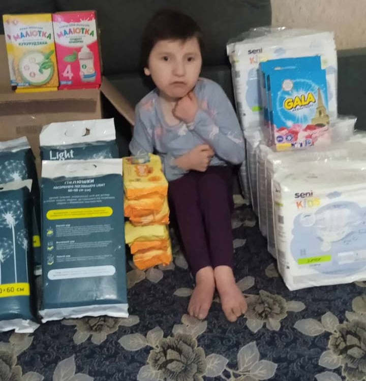 дівчинка сидить на дивані з великою кількістю підгузників