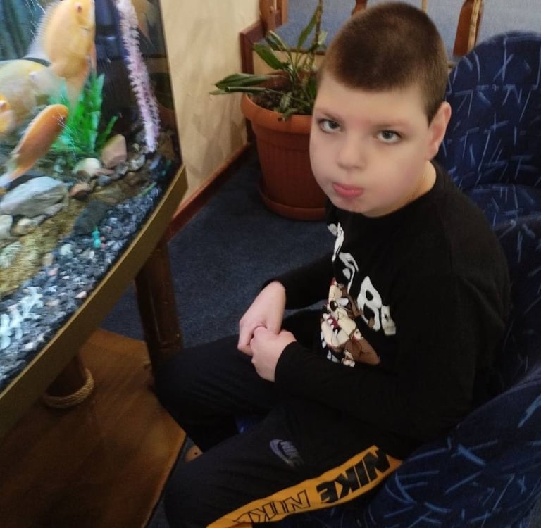 молодий хлопчик сидить у кріслі з акваріумом