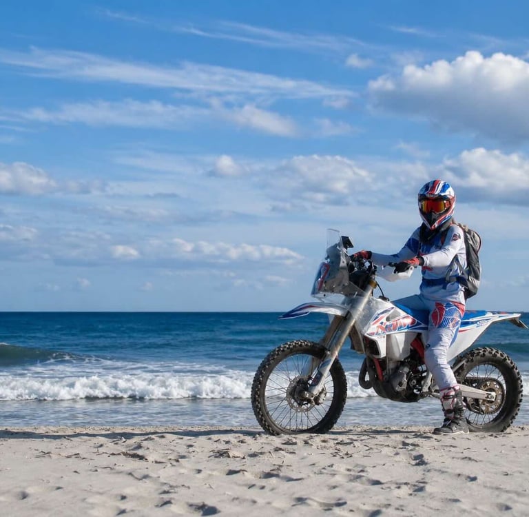 Anja auf ihrer Enduro am Strand mit dem Meer im Hintergrund