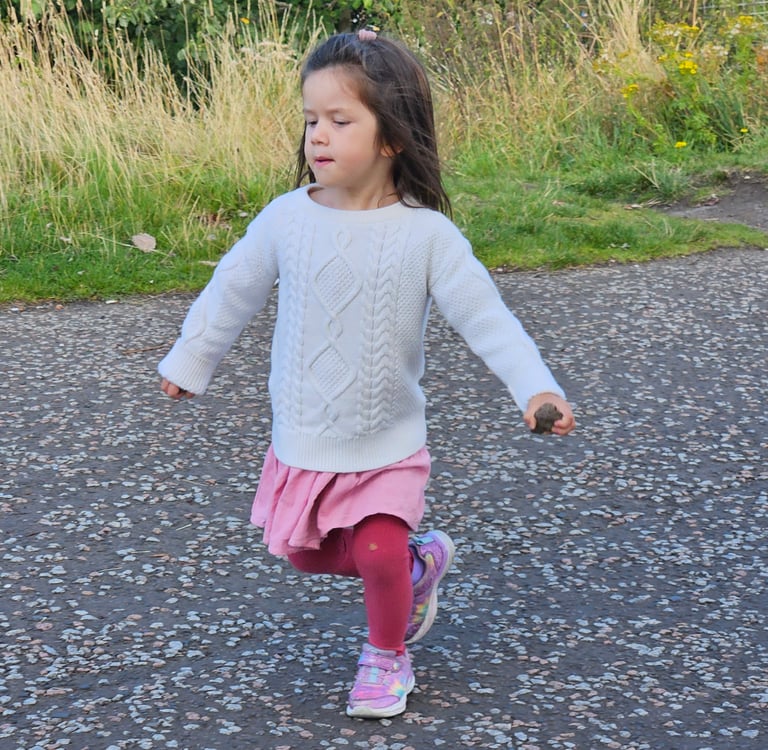 Girl running in Scotland in layered capsule wardrobe during a family trip to Europe