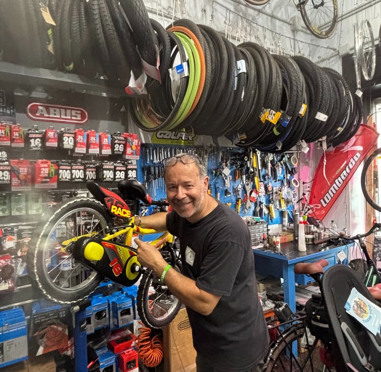 Federico, il proprietario di abicicomeprima, sorride intento ad aggiustare una bici da bambino