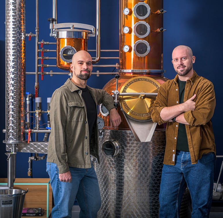 master distiller e designer in posa professionale davanti ad un alambicco di rame e acciaio