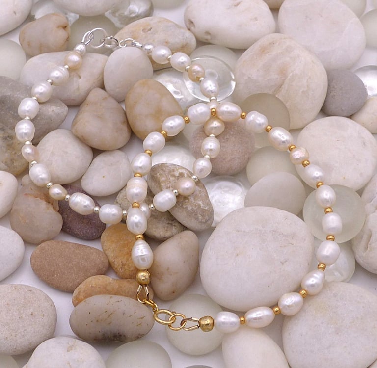 Elegant handmade freshwater pearl bracelets with gold and silver accents on smooth river stones.