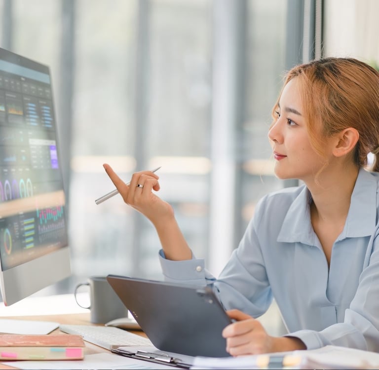 a woman sitting at a desk with a computer and a pen-ai integrated digital marketing
