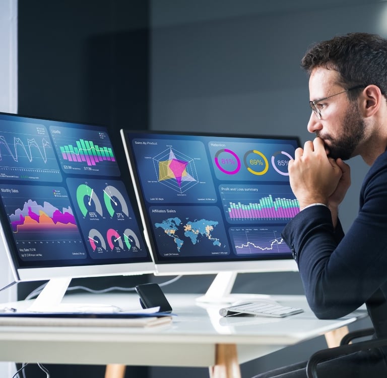a man sitting at a desk with two monitors and a laptop-digital marketing institution
