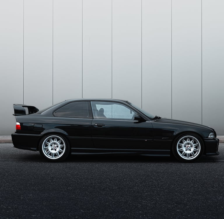 a black bmw m3 e36 parked in front of a building