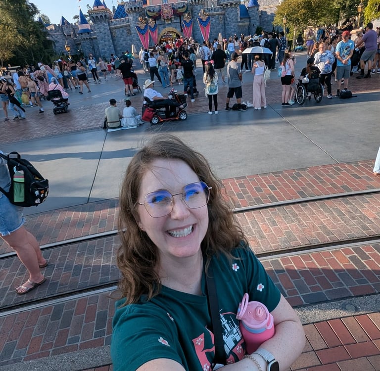 Katie Matzenbacher, standing in front of Sleeping Beauty's castle at Disneyland in California