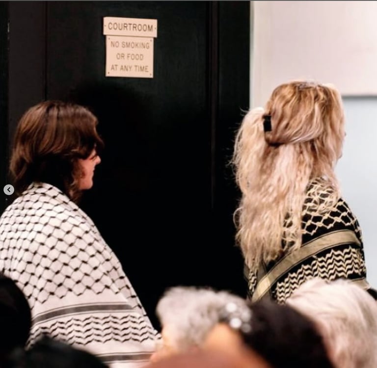 two women wearing keffiyehs walk out of a courtroom in Chapel Hill, NC