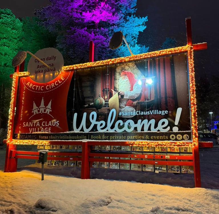 Illuminated Santa Claus Village welcome sign at the Arctic Circle in Rovaniemi Finland at night.