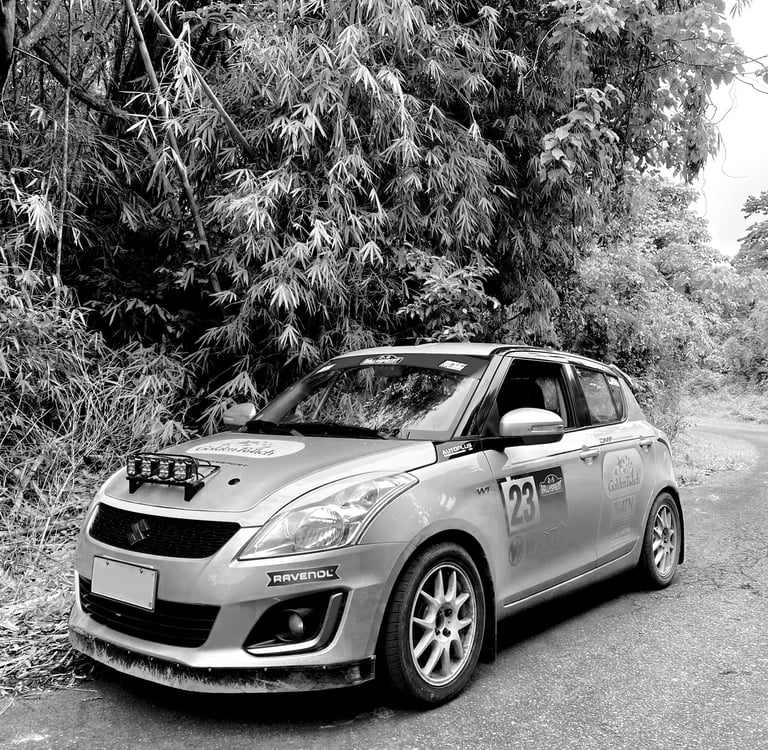 Rally car parked on an empty road with shrubbery and trees in the background