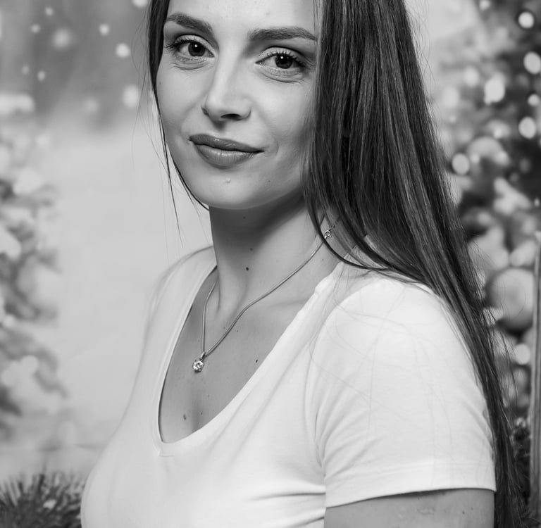 Black and white portrait of a woman with long hair and a necklace against a festive holiday background.