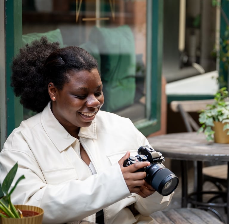 a black woman smiling in white jacket looking at outdoor photography photos